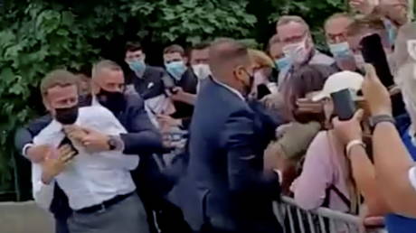 French President Emmanuel Macron is protected by a security member after getting slapped by a member of the public during a visit in Tain-L'Hermitage, France, in this still image taken from video on June 8, 2021. © BFMTV/ReutersTV via REUTERS