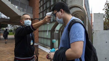 Taiwanese students get their temperature checked as they enter the Taipei American school on March 18, 2020 in Taipei, Taiwan. © Paula Bronstein/Getty Images