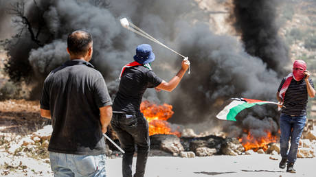 Palestinian protester uses slingshot during clashes with Israeli security forces in Beita, near Nablus, in occupied West Bank on June 11, 2021