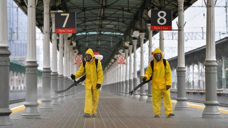 Russian Emergencies Ministry workers in protective gear disinfect a platform of the Belorussky railway station amid the coronavirus outbreak in Moscow. © Sputnik / Pavel Bednyakov.