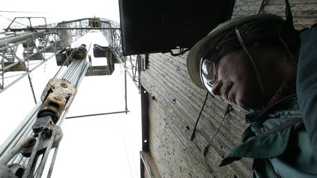 A Rosneft worker stands beneath a crane at the Yuganskneftegaz oil production station near the Siberian town of Nefteyugansk, Russia