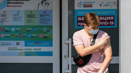 A young man wearing protective face mask and gloves walks after receiving a dose of Russian Gam-COVID-VAK (trademark 'Sputnik V'). © Sputnik / Ramil Sitdikov