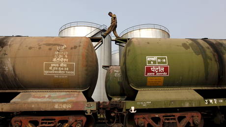 A worker walks atop a tanker wagon to check the freight level at an oil terminal on the outskirts of Kolkata, India