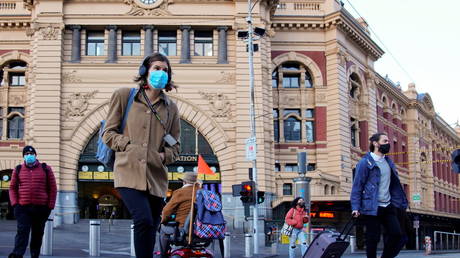 Pedestrians cross the road at Flinders Street Station on the first day of eased coronavirus disease (COVID-19) restrictions for the state of Victoria following an extended lockdown in Melbourne, Australia, June 11, 2021. © REUTERS/Sandra Sanders