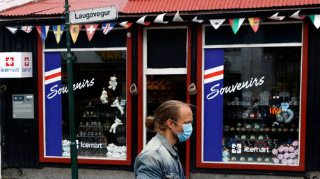 FILE PHOTO: A man with a face mask walks past a tourist shop in Reykjavik, Iceland on September 3, 2020. © REUTERS/John Sibley