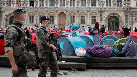 French soldiers walk past tents installed by migrants in front of the City Hall in Paris. © Reuters / Gonzalo Fuentes