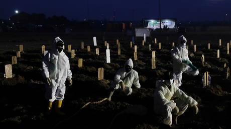 Gravediggers take a break as they work at the burial area provided for coronavirus victims, in Jakarta, Indonesia on June 28, 2021.