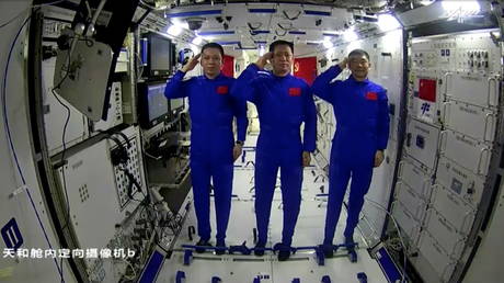 Chinese astronauts Nie Haisheng, Liu Boming and Tang Hongbo of the Shenzhou-12 mission salute as they speak to Chinese President Xi Jinping (not seen) via a video call from Tianhe core module of China's space station, in this still image taken from a video released June 23, 2021. © Reuters / CCTV
