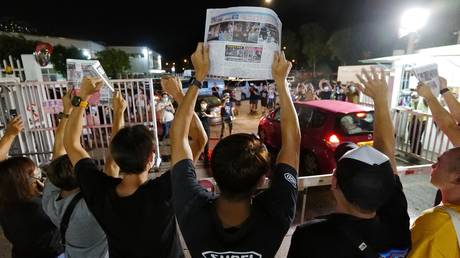 Apple Daily journalists hold freshly-printed copies of the newspaper's last edition while acknowledging supporters gathered outside their office in Hong Kong early on June 24, 2021. © AFP / Daniel SUEN