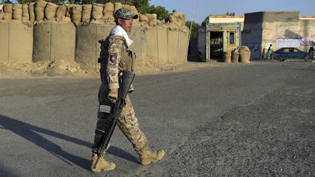 In this photo taken on June 3, 2021, a policeman walks outside his outpost along a roadside in Ghazni, Afghanistan.