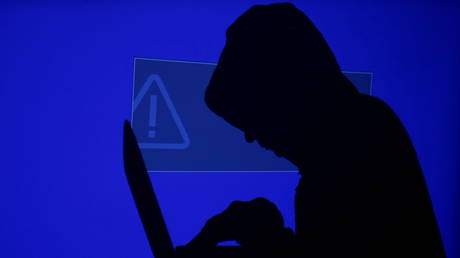 FILE PHOTO: A hooded man holds a laptop computer as a blue screen with an exclamation mark is projected on him in this illustration picture taken on May 13, 2017 © Reuters / Kacper Pempel