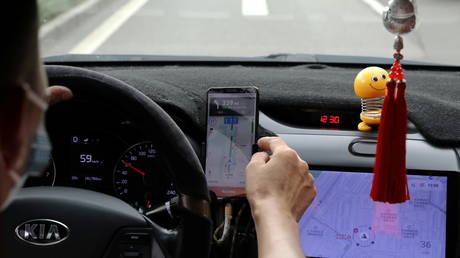 A driver of Chinese ride-hailing service Didi drives with a phone showing a navigation map on Didi's app, in Beijing, China July 5, 2021. © REUTERS/Tingshu Wang