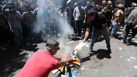 Anti-LGBT protesters burn a rainbow banner as they take part in a rally ahead of the planned March for Dignity during Pride Week in Tbilisi, Georgia July 5, 2021. © REUTERS/Irakli Gedenidze