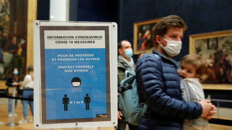 Visitors wearing protective face masks walk past a sign with health and safety measures for visitors at the Louvre museum in Paris, May 19, 2021. © REUTERS/Sarah Meyssonnier