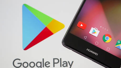 A smartphone is seen in front of displayed Google Play logo.