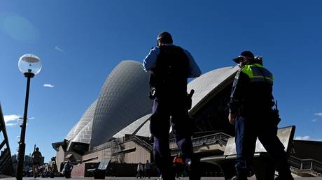 Police officers patrol the area outside the Sydney Opera House in Australia, June 2021. © Saeed Khan/AFP