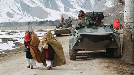 FILE PHOTO. Afghan women with children in their arms hurrying past Soviet armored vehicles along a serpentine highway outside Jalalabad, Afghanistan. © Sputnik