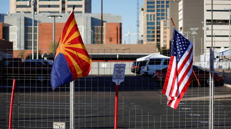 US and state flags fly outside a fenced-off protest space at the Maricopa County Tabulation and Election Center in Phoenix, Arizona, November 11, 2020.