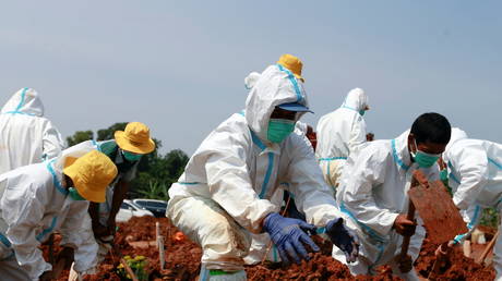 Gravediggers wearing personal protective equipment (PPE) bury a coffin at a Muslim burial area provided by the government for coronavirus disease (COVID-19) victims in Bekasi, on the outskirts of Jakarta, Indonesia, July 8, 2021. © REUTERS/Ajeng Dinar Ulfiana