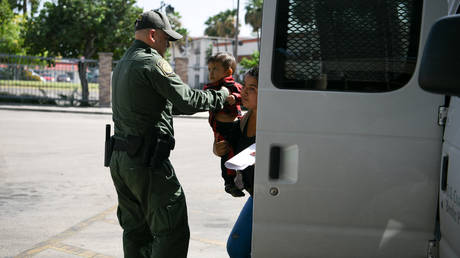 FILE PHOTO: A US Border Patrol agent assists a migrant woman and child as they're released from federal detention at a bus depot in McAllen, Texas, July 31, 2019.