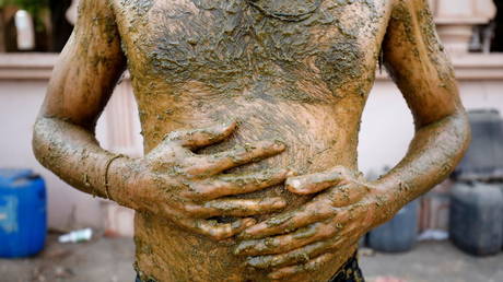 A man applies cow dung on his body during "cow dung therapy", believing it will boost his immunity to defend against the coronavirus disease (Covid-19) on the outskirts of Ahmedabad, India, (FILE PHOTO) © REUTERS/Amit Dave