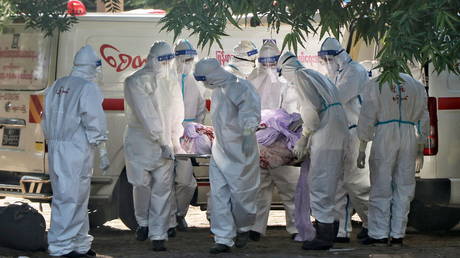 FILE PHOTO. Volunteers carry bodies of people who died due to the coronavirus disease at a cemetery in Mandalay, Myanmar.