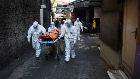 Health workers removed the body of a Covid-19 victim who died while isolating at home in Bandung on July 18, 2021, as skyrocketing Covid-19 infections and deaths are overwhelming hospitals. © AFP / Timur Matahari