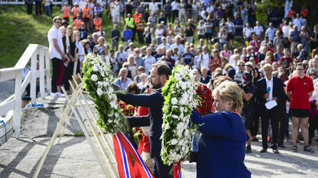 Crown Prince Haakon of Norway (L) and Prime Minister Erna Solberg (R) lay wreaths during a memorial ceremony at Utoya on July 22, 2016