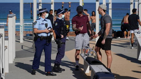 Police officers check IDs as they enforce a coronavirus lockdown at an outdoor gym area at Bondi Beach, in Sydney, Australia, July 27, 2021.