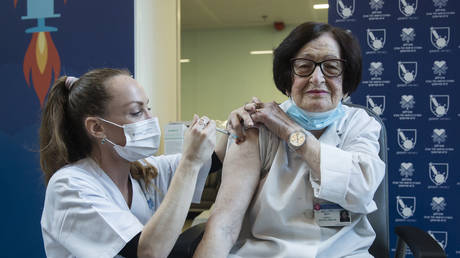 随着以色列于 2020 年 12 月 20 日在以色列特拉维夫开始 COVID 19 疫苗接种活动，92 岁的 Verona Radosh 医生在特拉维夫 Sourasky 医疗中心由一名医务人员接种了针对冠状病毒病 (COVID-19) 的疫苗。 © Amir Levy/Getty Images