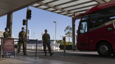 Army personnel watch as a charter bus that unloaded crew from the Ruby Princess Cruise ship departs Sydney Airport on April 23, 2020 in Sydney, Australia. © Brook Mitchell/Getty Images