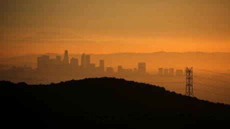 Los Angeles skyline is seen behind an electricity pylon at sunrise in Los Angeles, California, US
