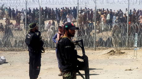 Pakistan's paramilitary soldiers stand guard in front of people who gather and wait to cross at the Friendship Gate crossing point in the Pakistan-Afghanistan border town of Chaman, Pakistan August 12, 2021 © REUTERS/Abdul Khaliq Achakzai