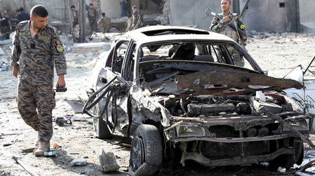 A member of Afghan security forces looks at a damaged car at the site of yesterday's night-time car bomb blast in Kabul, Afghanistan August 4, 2021.