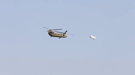 A blimp passes in the sky as a U.S. Army Chinook helicopter flies over Kabul, Afghanistan August 15, 2021