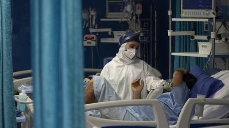 Medical personnel wearing a protective suit speaks with an Iranian-Arab man who has recovered from the new coronavirus disease, in a COVID-19 ward in Golestan hospital in the city of Ahvaz 817Km south of Tehran in Khouzestan province on March 14, 2021. © Morteza Nikoubazl/NurPhoto via Getty Images