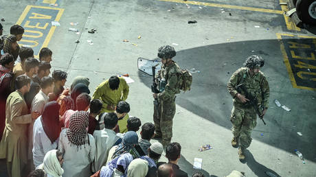 US soldiers stand guard as Afghan people wait at the Kabul airport in Kabul on August 16, 2021 © Wakil Kohsar / AFP