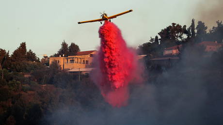 A firefighting plane disperses fire retardant near the Israeli village of Beit Meir on the outskirts of Jerusalem on August 16, 2021.