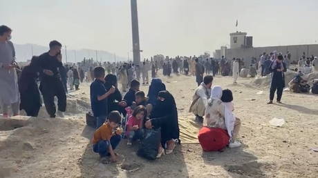 People gathered outside the Hamid Karzai International Airport react to gunfire as US troops oversee an evacuation effort, in Kabul, Afghanistan, August 18, 2021.