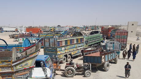 People walk past trucks loaded with supplies, waiting to cross into Afghanistan at the Friendship Gate crossing point in the border town of Chaman, Pakistan, August 18, 2021.