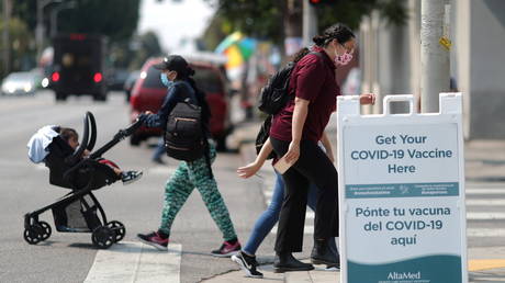 People walk past a sign for a coronavirus disease (COVID-19) vaccination clinic in Los Angeles, California