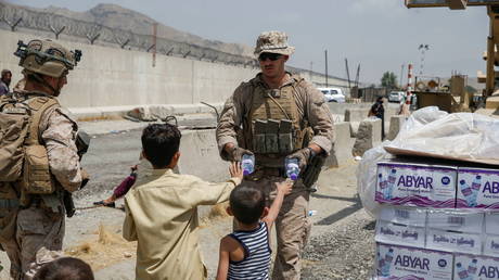 A US Navy Corpsman hands out water to children during an evacuation at Hamid Karzai International Airport in Kabul, Afghanistan, August 20, 2021 © Reuters / Lance Cpl. Nicholas Guevara / US Marine Corps