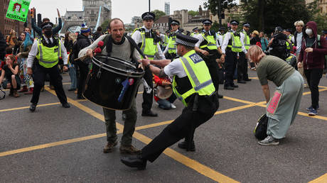 An Extinction Rebellion climate demonstrator clashes with a police officer, as protesters block a road to Tower Bridge during a protest in London, Britain, August 30, 2021. © Reuters / Tom Nicholson