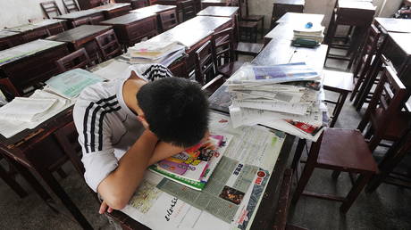 A student takes a nap on his desk during the lunch time after the extra tuition at a school in Hefei. AFP Photo © STR / AFP