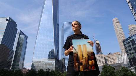 A docent at the 9/11 Tribute Museum, stands in front of One World Trade Center