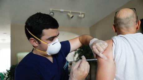 A pharmacy technician administers the Pfizer-BioNTech Covid-19 vaccine to Mike Payne, a federal employee, at his home in St. Petersburg, Florida, July 30, 2021 © Reuters / Octavio Jones
