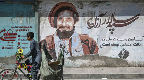 A boy peddles past a wall painting with a portrait of late Afghan commander Ahmad Shah Massoud in Kabul on September 8, 2021. © Aamir QURESHI / AFP