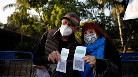 FILE PHOTO: A couple pose for a photo with their "Green Pass" before they enter a live performance by Israeli singer Nurit Galron at Yarkon park, Tel Aviv, Israel February 24, 2021 © Reuters / Amir Cohen