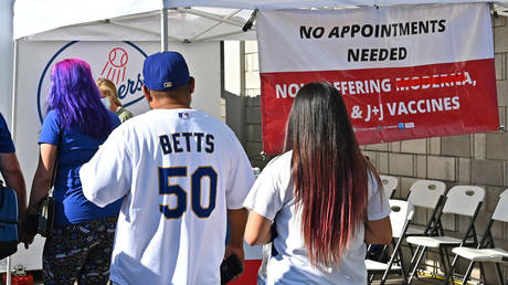 FILE PHOTO: Fans are shown walking by a vaccination clinic outside Dodgers Stadium, offering free tickets to those who get inoculated, in July.