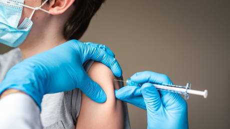 Stock photo: Child wearing mask getting vaccinated by doctor holding a needle © Getty images